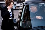 Corporate Guy Interacting With Taxi Driver Stock Photo