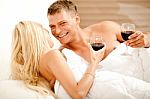 Couple Enjoying Wine In Bed Stock Photo