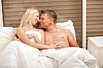 Couple Lying In Bed Smiling Stock Photo