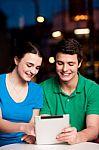 Couple Using Tablet Computer At An Outdoor Cafe Stock Photo