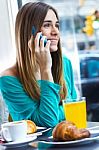 Cute Brunette Woman In Cafe Is Speaking By Mobile Phone Stock Photo