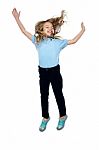 Delighted Young Girl Jumping High In The Air Stock Photo