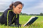 Dutch Woman Lying In Grass Reading Book Stock Photo