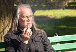 Elderly Gray-haired Man In Glasses Smoking A Cigarette Stock Photo