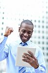 Executive Celebrates His Success Holding A Tablet Stock Photo