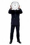 Executive Holding Up Wall Clock In Front Of His Face Stock Photo