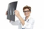 Experienced Female Doctor Examining X-ray Report Stock Photo