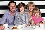 Family Of Four Having Great Time In Restaurant Stock Photo