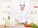 Female Chef Cutting Onions On The Cutting Board In Kitchen Stock Photo