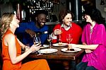 Four Friends Enjoying Dinner At A Restaurant Stock Photo