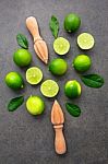 Fresh Limes And Wooden Juicer On Dark Stone Background. Top View Stock Photo