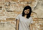 Girl Posing And Smiling While Standing Near Brick Wall Stock Photo