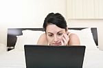 Girl Relaxing On Bed With Laptop Stock Photo