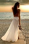 Girl Walking On The Beach At Sunset Stock Photo