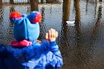 Girl Waving A Paper Boat Floating In The Creek Stock Photo