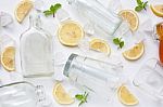 Glasses And Bottle For Drinks With Lemon Slices, Mint And Honey Stock Photo