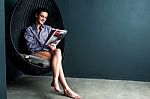 Gorgeous Woman Reading Magazine, Sitting On Bubble Chair Stock Photo