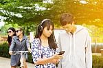 Group Of Asian Teenager Walking In The Park And Enjoyed Watching Video From Smartphone  Stock Photo