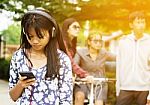 Group Of Asian Teenager Walking In The Park And Enjoyed Watching Video From Smartphone  Stock Photo