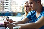 Group Of Friends Using Mobile Phone In Cafe Stock Photo