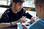 Group Of Friends Using Mobile Phone In Cafe Stock Photo