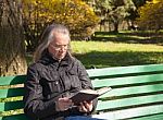 Haired Elderly Man Reading A Book Sitting On A Bench In City Par Stock Photo