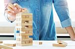 Hand Of Engineer Playing A Blocks Wood Tower Game (jenga) On Blu Stock Photo