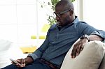 Handsome Young Man Using His Mobile Phone At Home Stock Photo