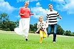 Happy Family Running In Park Stock Photo