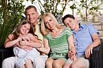 Happy Family Sitting In Patio And Looking At You Stock Photo