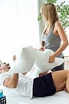 Happy Young Couple Playing With Pillows In The Sofa Stock Photo