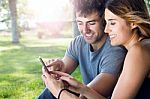 Happy Young Couple With Smartphone At The Park Stock Photo