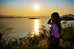 Happy Young Woman Standing Watching The Sunset Over The Lake Stock Photo