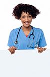 Joyous Female Doctor Standing Behind Ad Board Stock Photo