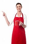 Joyous Female With Coffee Mug Pointing Away Stock Photo