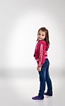 Little Girl In Blue Jeans And A Red Jacket In The Studio Stock Photo