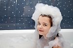 Little Girl Sitting In A Bath With Soap Suds Stock Photo