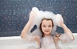 Little Girl Sitting In A Bath With Soap Suds On Her Head Stock Photo