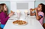 Little Girls Enjoying Pizza In A Restaurant Stock Photo