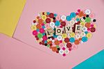 Love Word Written On Wooden Block Placed On Colourful Button In Stock Photo