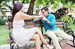 Loving Young Couple Flirting While Sitting At A Park Bench Stock Photo