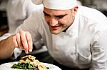 Male Chef Decorating Salad Of Goat Cheese Stock Photo