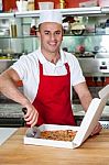 Male Chef Using Pizza Cutter Stock Photo