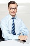 Man Sitting On Chair Using Laptop In Office Stock Photo