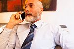 Middle-aged Businessman Listening On Smartphone At Home Stock Photo