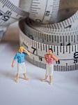 Miniature Woman Standing Near Measuring Tape, Thinking Of Weight Stock Photo