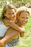 Mom Giving Piggyback Ride To Child Stock Photo