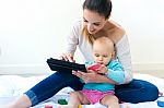 Mother And Baby Girl Using Digital Tablet At Home Stock Photo