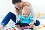 Mother And Baby Girl Using Digital Tablet At Home Stock Photo