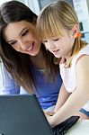 Mother And Daughter Using Laptop In The Kitchen Stock Photo